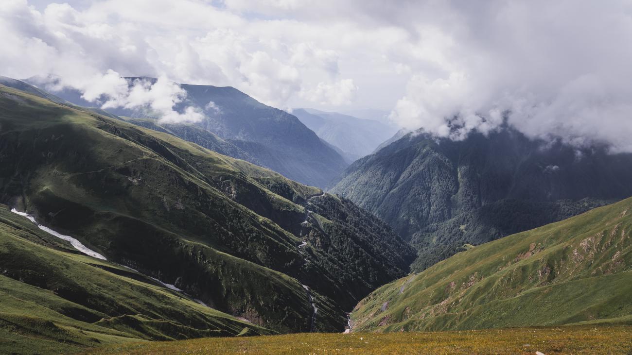 Green valley and mountain landscape with clouds in Tusheti, Georgia