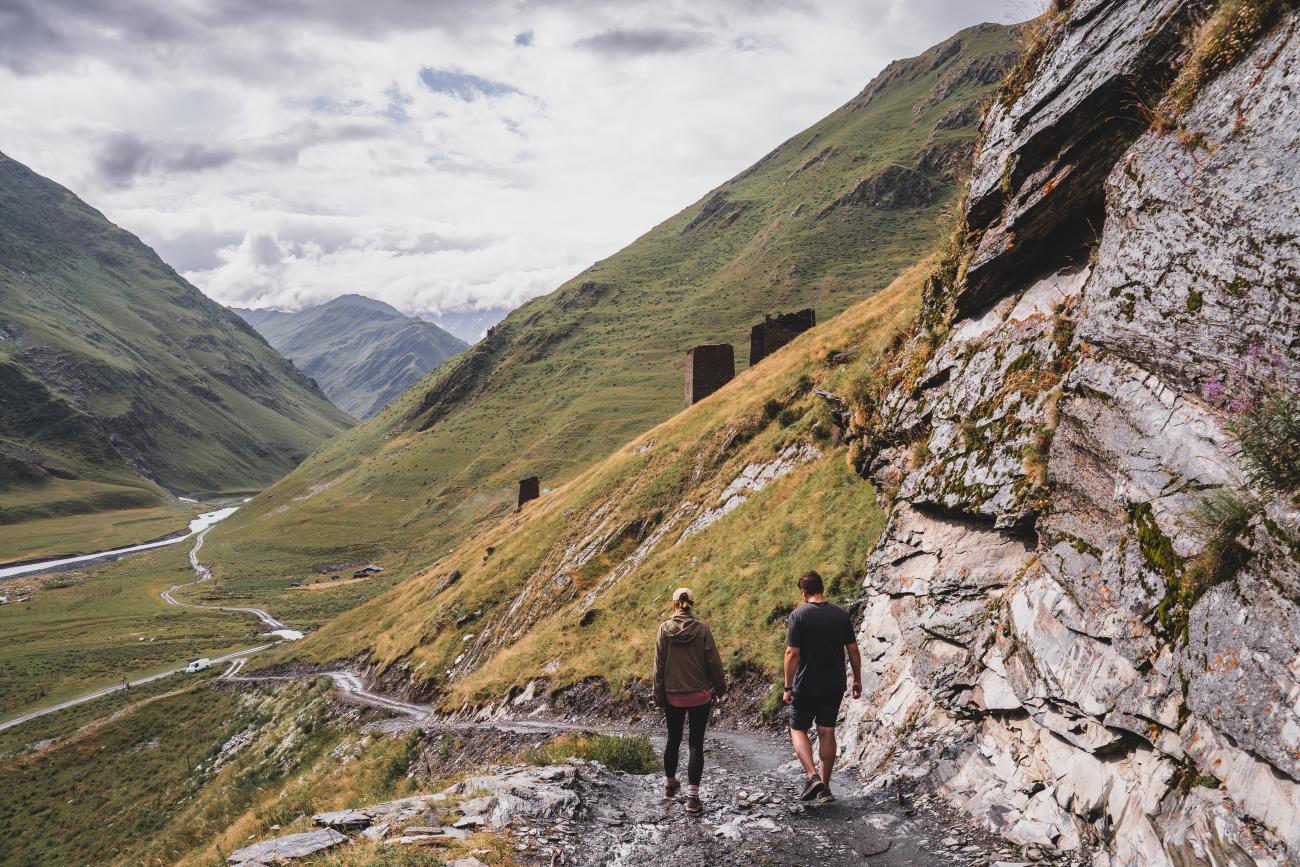 Man and woman walking on a muddy mountain path in the valley of Tusheti, Georgia
