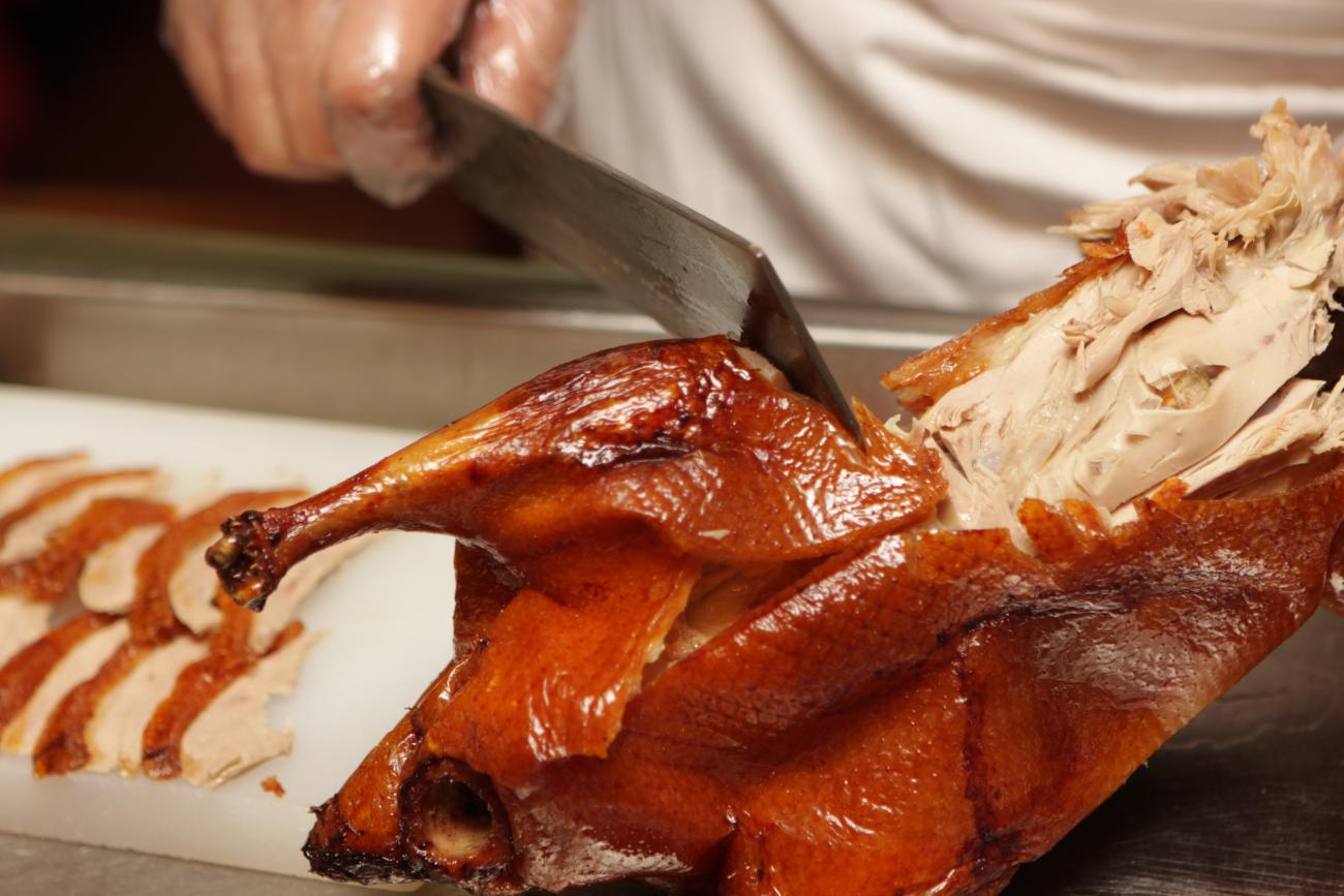 Closeup of a chef cutting up peking duck 
